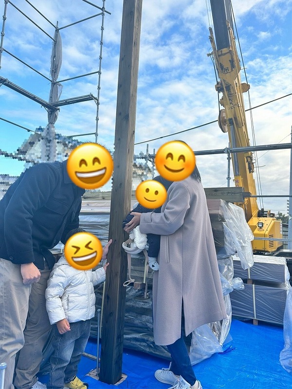 建築工房いろはが手がける注文住宅の建築現場で、家族が柱の前に集まり家づくりの節目を見守る様子を撮影した写真。
