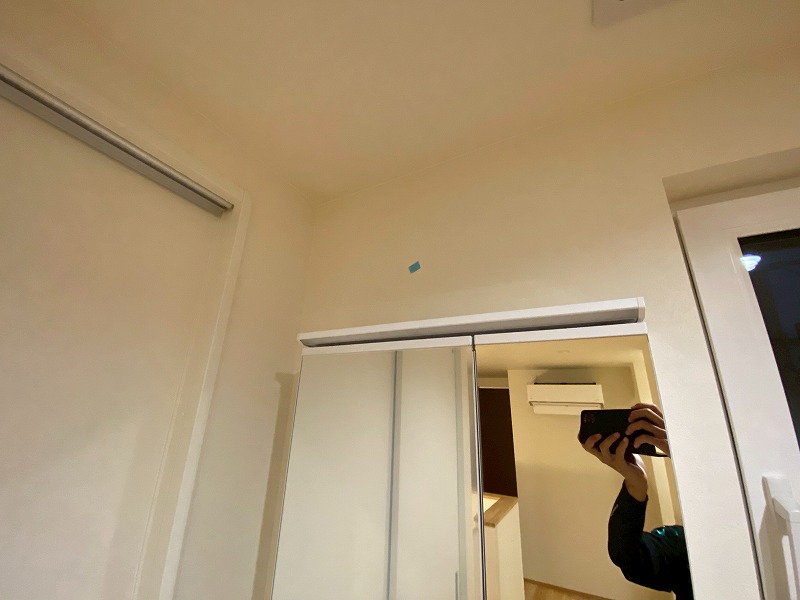 建築工房いろはが施工した注文住宅の引渡し前検査において、洗面脱衣室の壁と収納扉まわりに見つかった軽微な傷をマスキングテープで示しながら確認している様子を撮影した写真で、家づくりを支える工務店の品質管理工程を客観的に表現している。