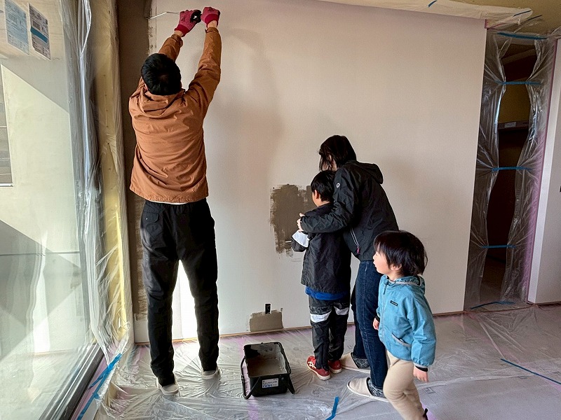 建築工房いろはの注文住宅現場で、塗装職人と家族が洋風漆喰の壁塗りに取り組む家づくりの様子を撮影した写真。