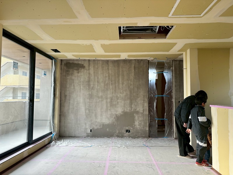 建築工房いろはの注文住宅現場で、洋風漆喰の施工中に家族が内装の進捗を見守る家づくりの様子を撮影した写真。