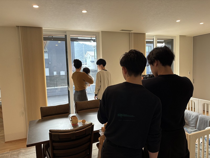 大きな窓から自然光が差し込む注文住宅のダイニング・リビング空間で、建築工房いろはが手がけた家づくりの一例として、家族や来客が集う様子が写された写真。