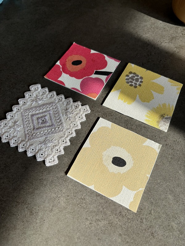 建築工房いろはの施主が家づくりで余ったクロスやフロアタイルを活用して制作した、花柄やレース模様のオリジナルコースターを並べた写真。