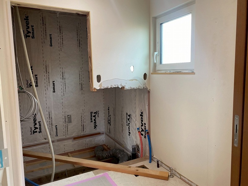 UBの解体後の施工現場で、断熱材や配管が露出した壁内部の様子を写した家づくりの構造写真。