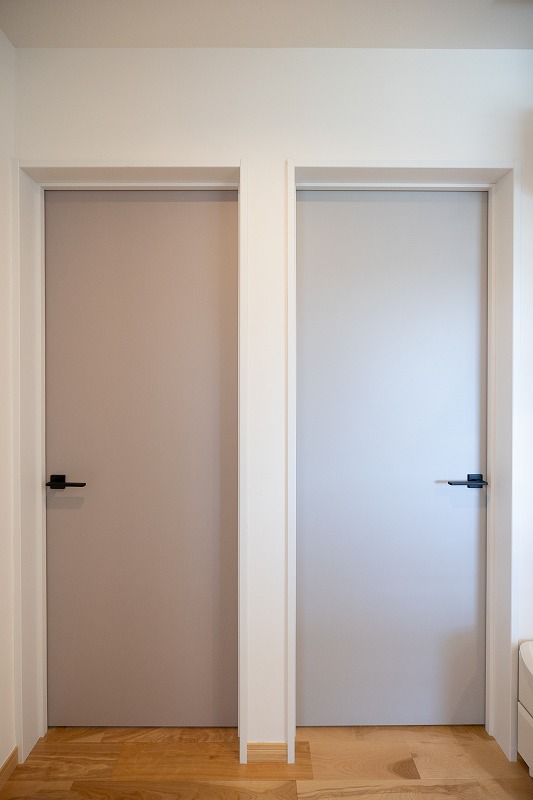 建築工房いろはが施工した注文住宅の室内において、色味の異なる2枚の室内ドアを並べて設けた廊下空間を撮影した写真で、家づくりにおける建具デザインや内装計画を工務店の施工事例として客観的に示している。