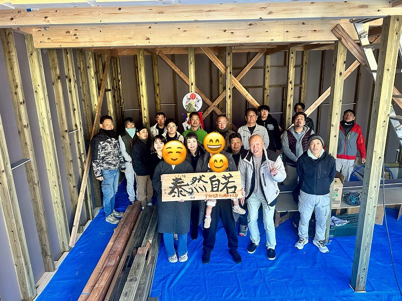 建築工房いろはが手がける木造注文住宅の上棟式にて、施主様とスタッフ・関係者が構造体内で記念撮影を行う様子が写る。