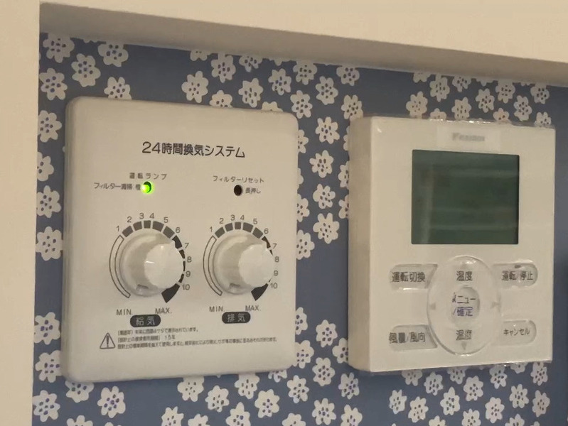 ALTテキスト（社名オプション：建築工房いろは）：
建築工房いろはが家づくりや注文住宅のメンテナンスとして、室内壁に設置された24時間換気システムの操作盤と空調リモコンを写した写真で、お手入れ後のランプの状態をを客観的に示す内容。