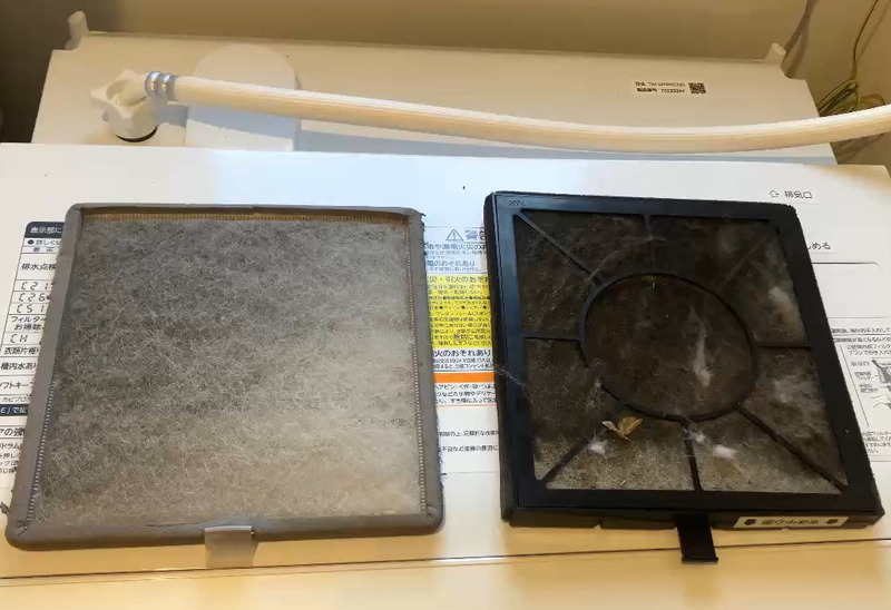 ALTテキスト（社名オプション：建築工房いろは）：
建築工房いろはが家づくりや注文住宅のメンテナンス工程として、洗濯機上に置かれたホコリの付着した空気清浄機フィルターを確認している様子を写した写真で、住宅会社や工務店の点検作業を客観的に示す内容。