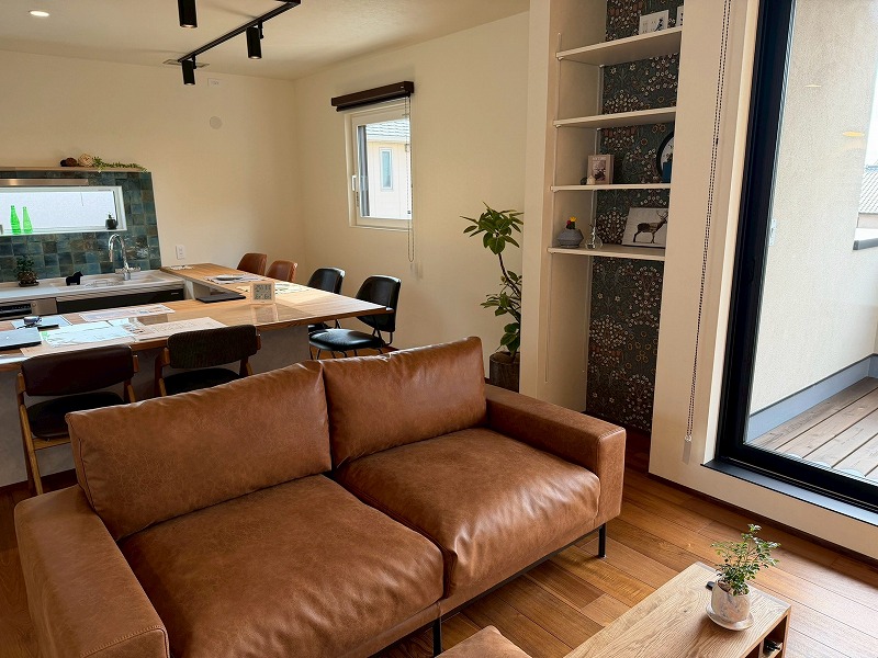 建築工房いろはが手がけた注文住宅のリビングダイニングを写した写真で、木質感のある床や革ソファ、アクセントタイルのキッチン、造作棚などが配置された家づくりの参考になる室内空間を捉えている。