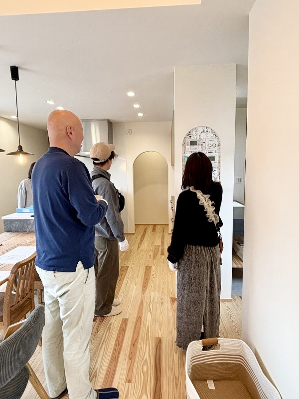 加古川市の注文住宅見学会で、建築工房いろはが手掛けた無垢床と勾配天井のLDKを来場者が確認している様子を写した室内写真で、家づくりや工務店選びの参考となる空間デザインが分かる内容です。