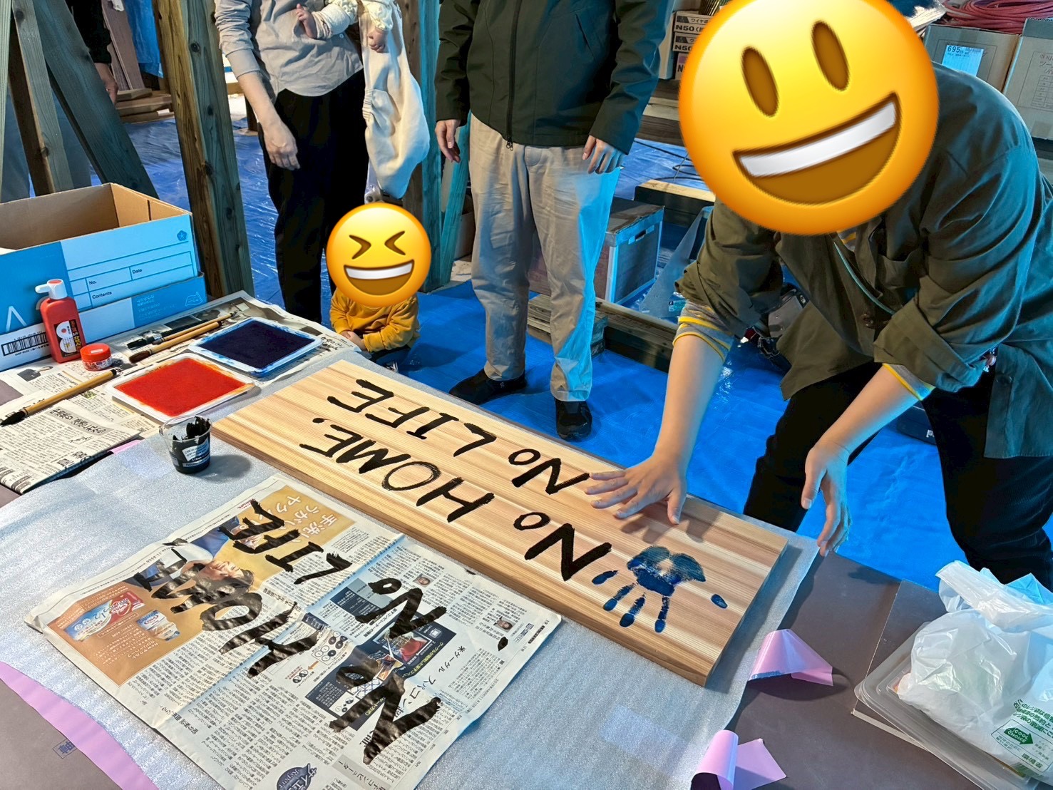 無垢材の板に「No HOME, No LIFE」の文字と青い手形を施す、家族参加型の家づくりイベントの様子。
