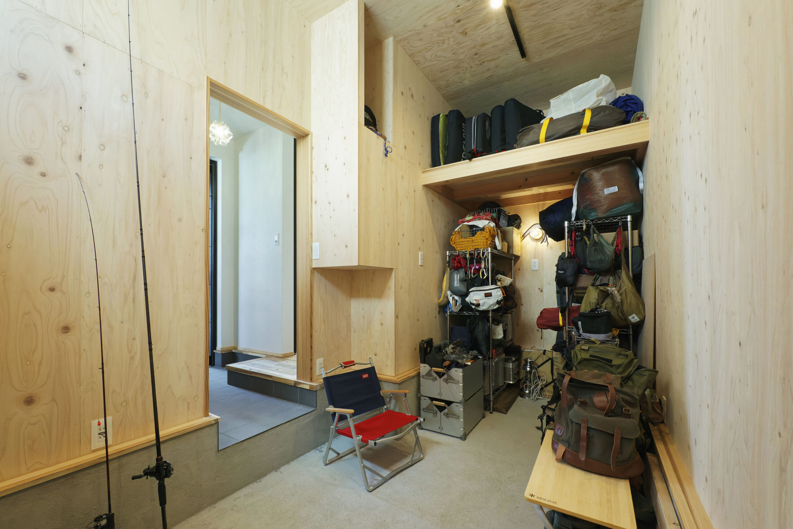 針葉樹合板の壁面がラフで隠れ家のような雰囲気を演出する、広々とした土間収納。釣り竿やキャンプ用品などのアウトドアギアを機能的にディスプレイ収納でき、趣味を存分に楽しめるガレージのような空間です。