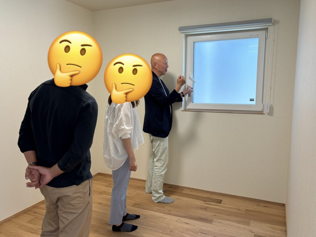完成した住宅の前で、テープカットを行い笑顔で喜びを分かち合うご家族の姿。木目調のアクセントウォールと黒い玄関ドアが際立つ、思い出深い引き渡しの記念風景。