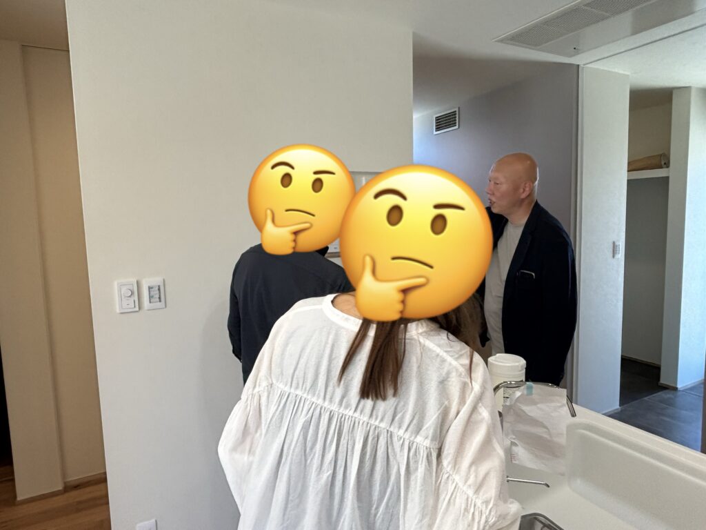 完成した住宅の前で、テープカットを行い笑顔で喜びを分かち合うご家族の姿。木目調のアクセントウォールと黒い玄関ドアが際立つ、思い出深い引き渡しの記念風景。