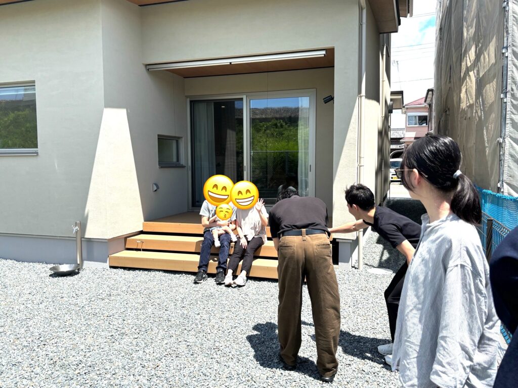 塗り壁の外壁にウッドデッキを設けた、家族が集う明るく開放的な住まいの庭先。