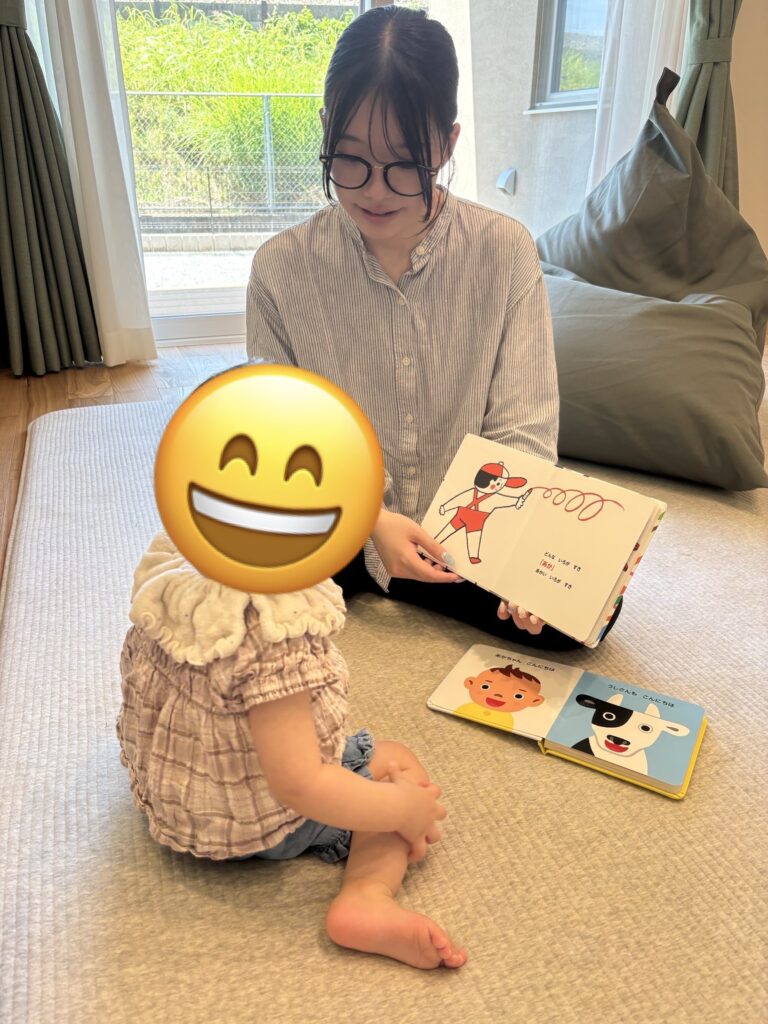 明るい自然光が差し込むリビングで、母親が子供に絵本を読み聞かせている、穏やかな団らんの様子。