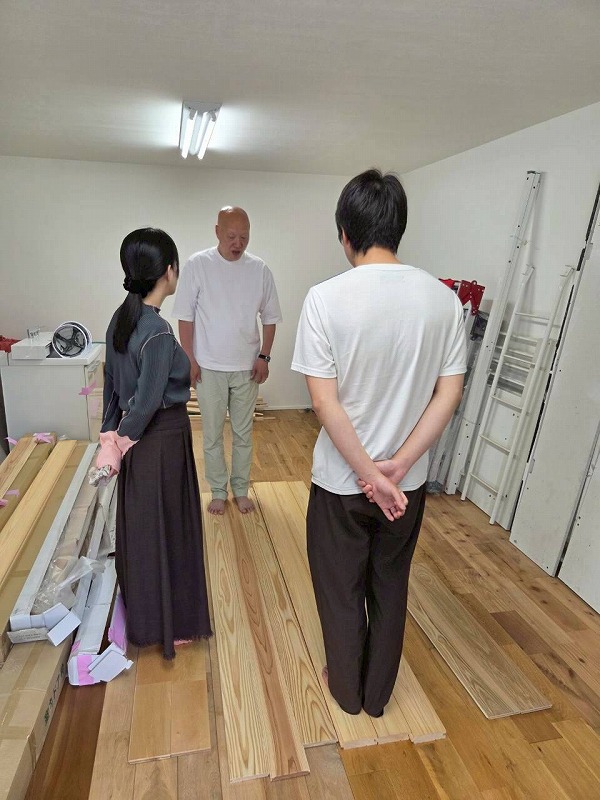 フローリング材を床に並べ、質感や色合いを確認しながら打ち合わせを行う施主と工務店担当者の様子。