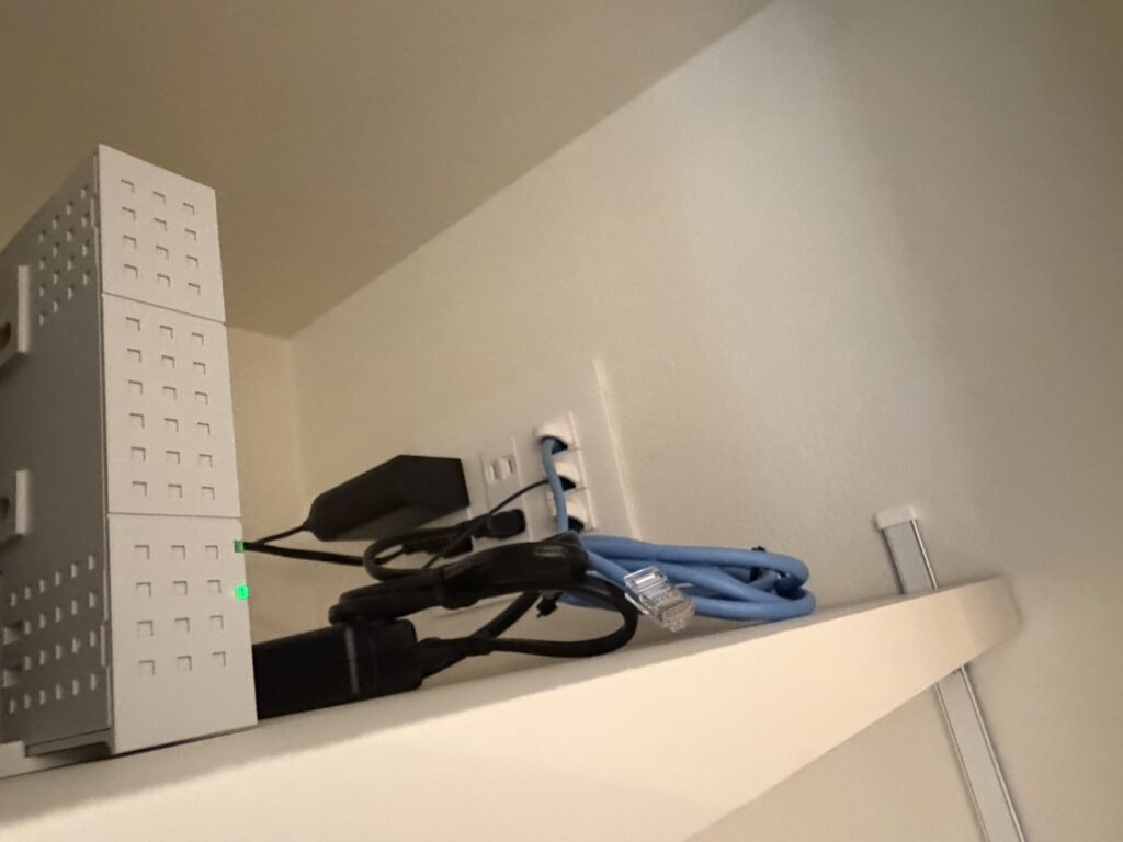 配線やルーターなどの通信機器がすっきりと収められた、機能的な収納スペースの一角。