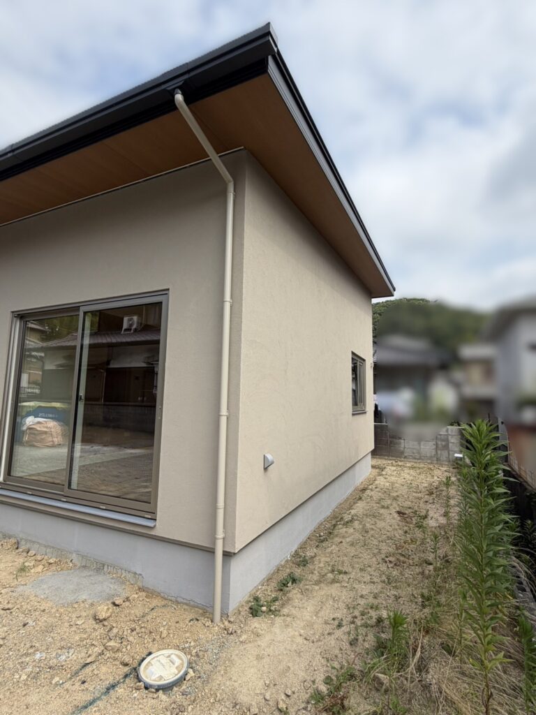 落ち着いた色合いの外壁に、木目の軒天とすっきりとしたサッシが映える住宅の外観。