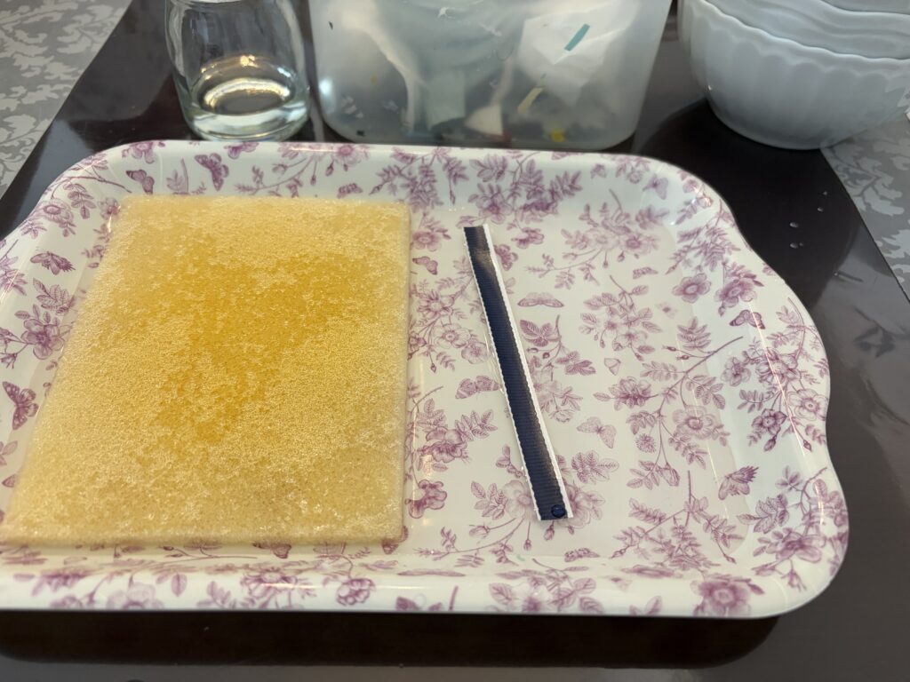 花柄模様のトレイの上に置かれた、ポーセラーツ制作で使用するスポンジと転写紙のストライプパーツ。