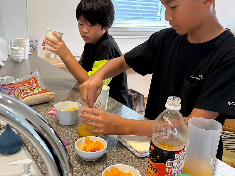 広々としたキッチンカウンターで、フルーツやカップを使って楽しそうに作業をする子どもたち。
