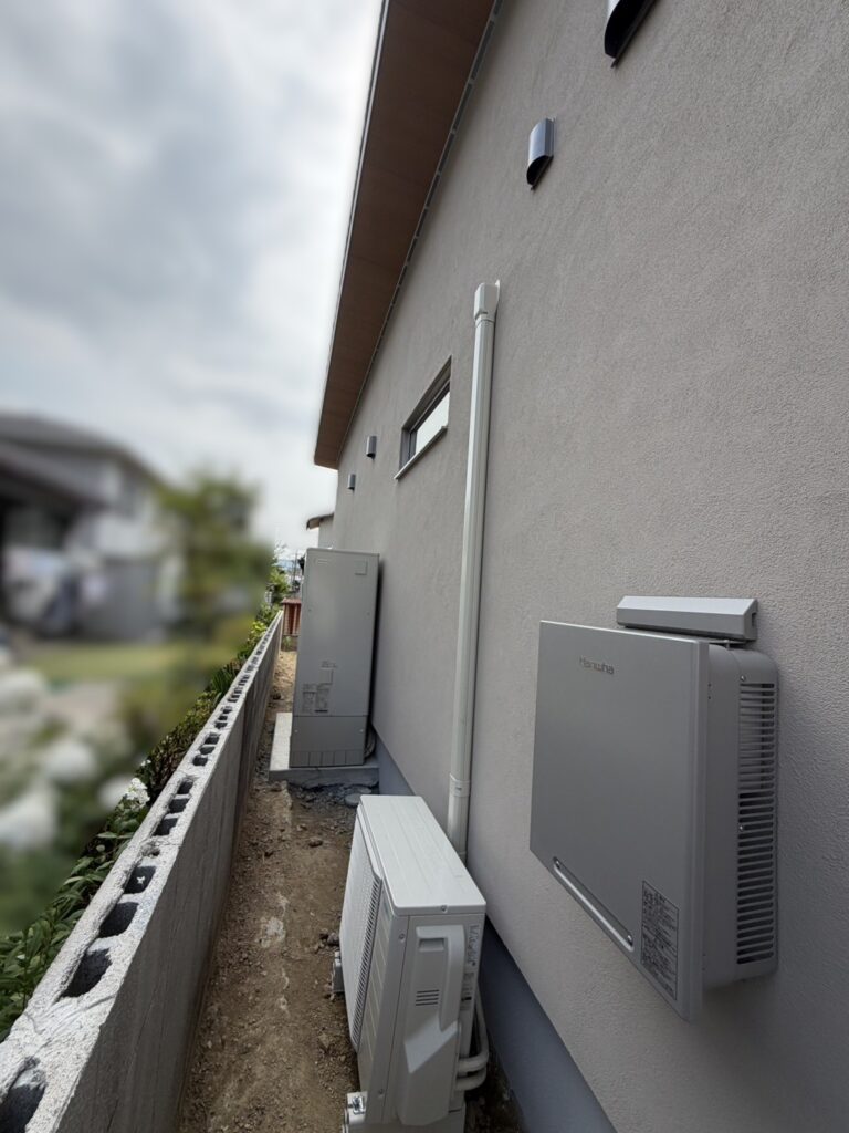 外壁に給湯器や室外機などの設備機器がすっきりと配置された、住宅のサイドスペースの様子。