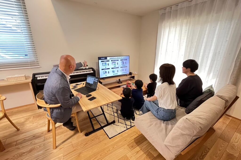 無垢フローリングのリビングでモニター画面を見つめながら、専門スタッフから住まいづくりの説明を受ける家族