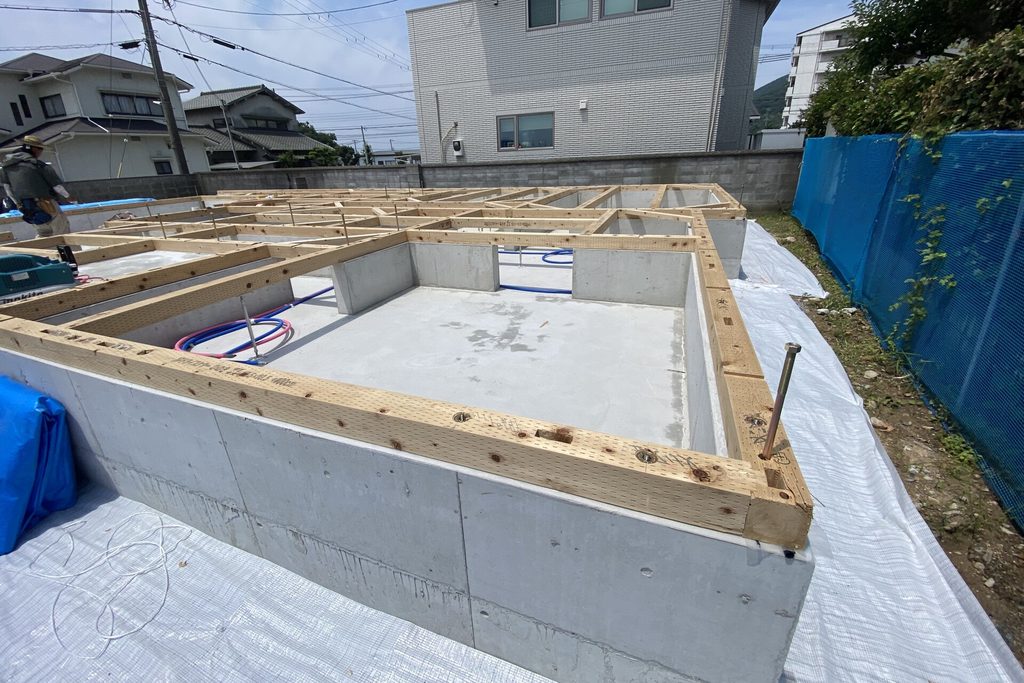 ベタ基礎の立ち上がりコンクリートの上にアンカーボルトで土台敷きが施工された、木造住宅の建築現場