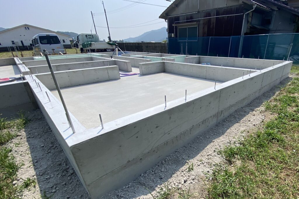 鉄筋入りのコンクリート基礎が完成した建築現場で、内部区画が形成された住宅の基礎構造が見える施工初期の様子。