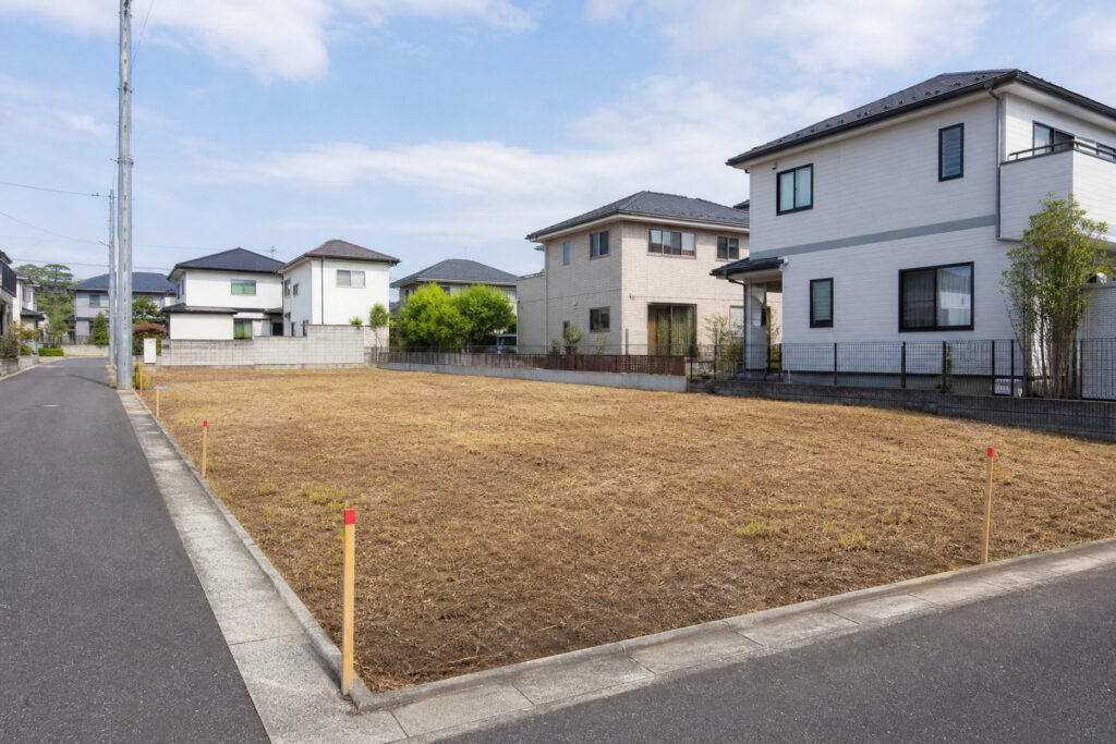 建築工房いろはが新築計画を進める際に扱う住宅用地の一例として、更地と周囲の戸建て住宅が並ぶ街並みを写した写真で、土地探しや家づくりの初期段階を客観的に示している。